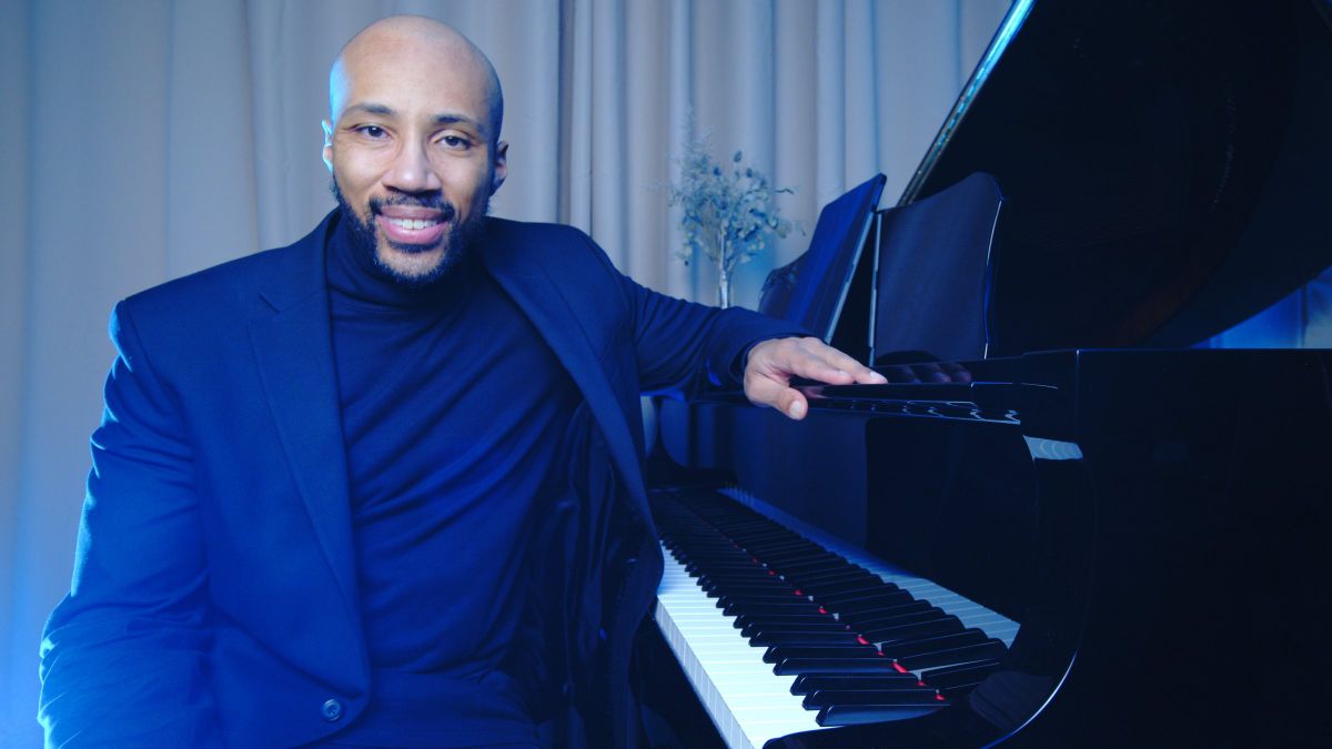 Jeremy Ajani Jordan, Artistic Director of The Elite Pianist, seated at a grand piano